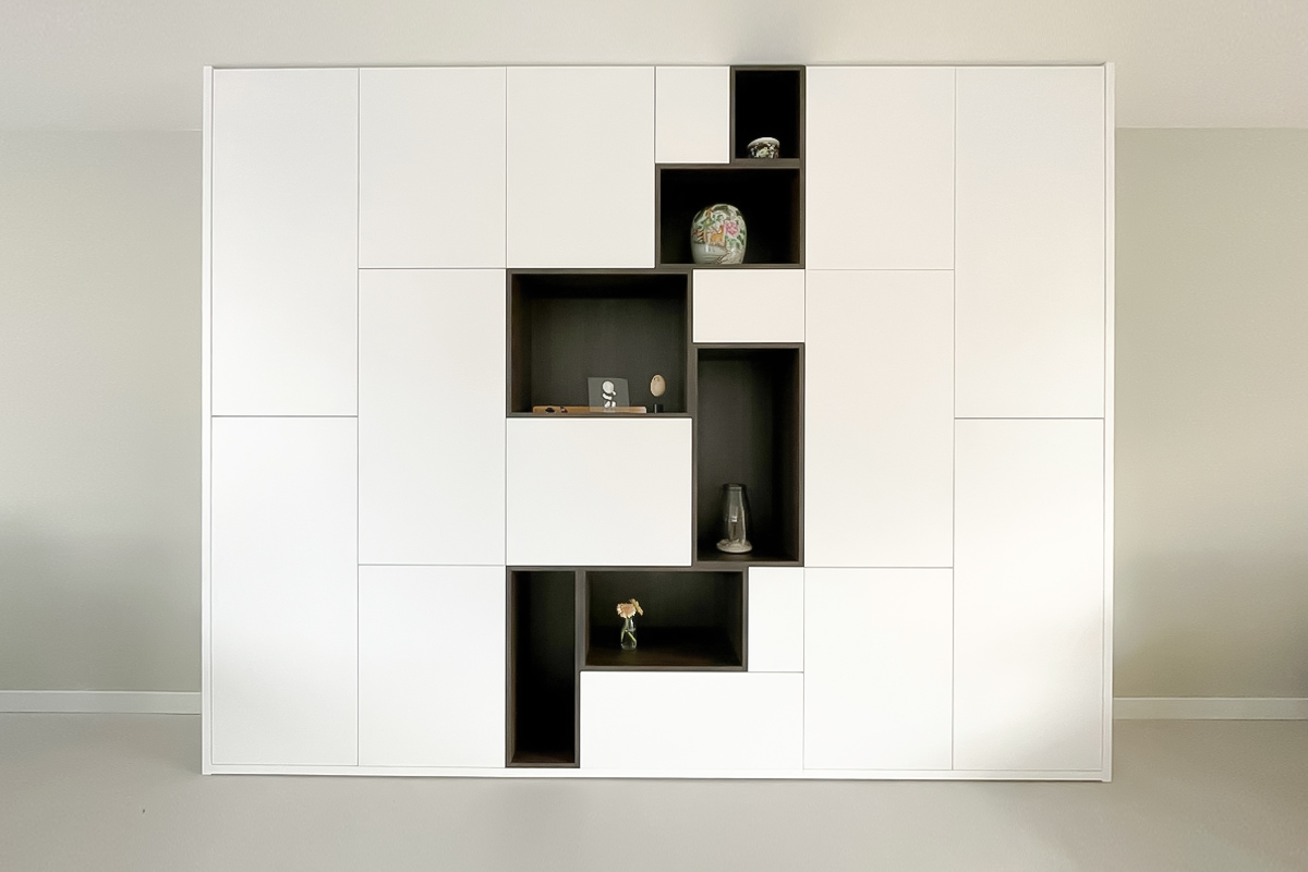Design kast op maat woonkamer met veel opbergruimte en nissen in een donkere houtkleur met accessoires.