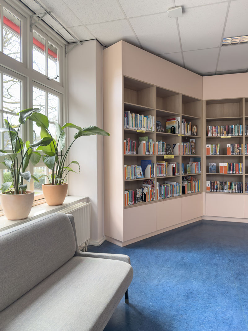 Boekenkast in teamkamer van basisschool Pallas Athene met planten en bank.