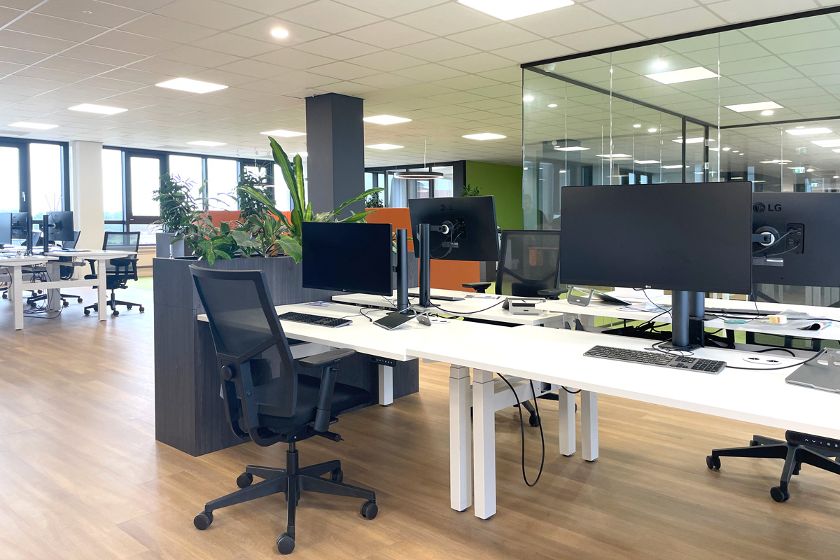 Open kantoortuin met zit-sta bureaus.