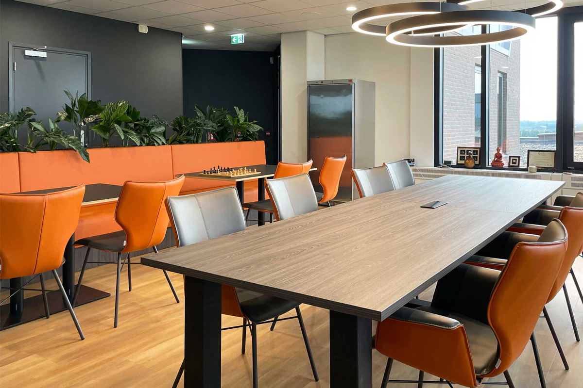 Inrichting kantine met maatbank met planten en industriële hanglampen.