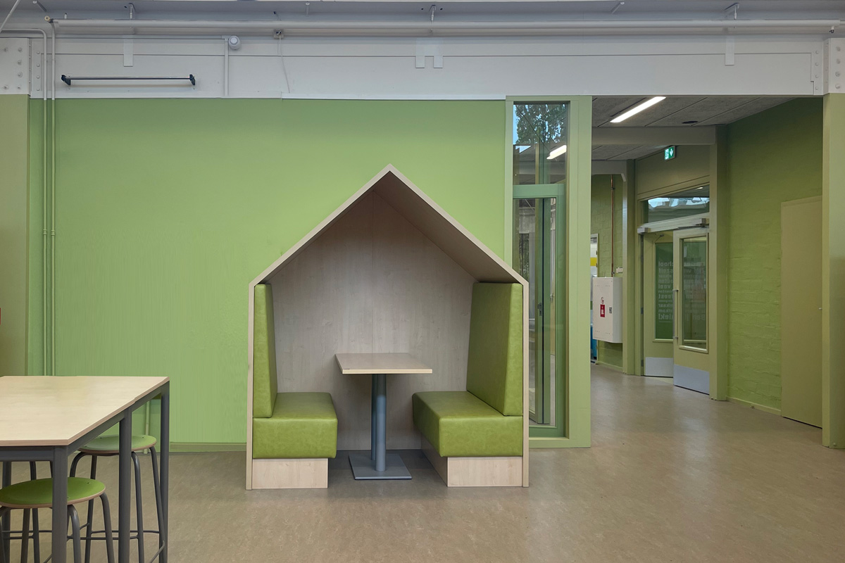 Leerplein in het schoolgebouw van basisschool Het Baken met groene wand en concentratiehuisje met groene banken.