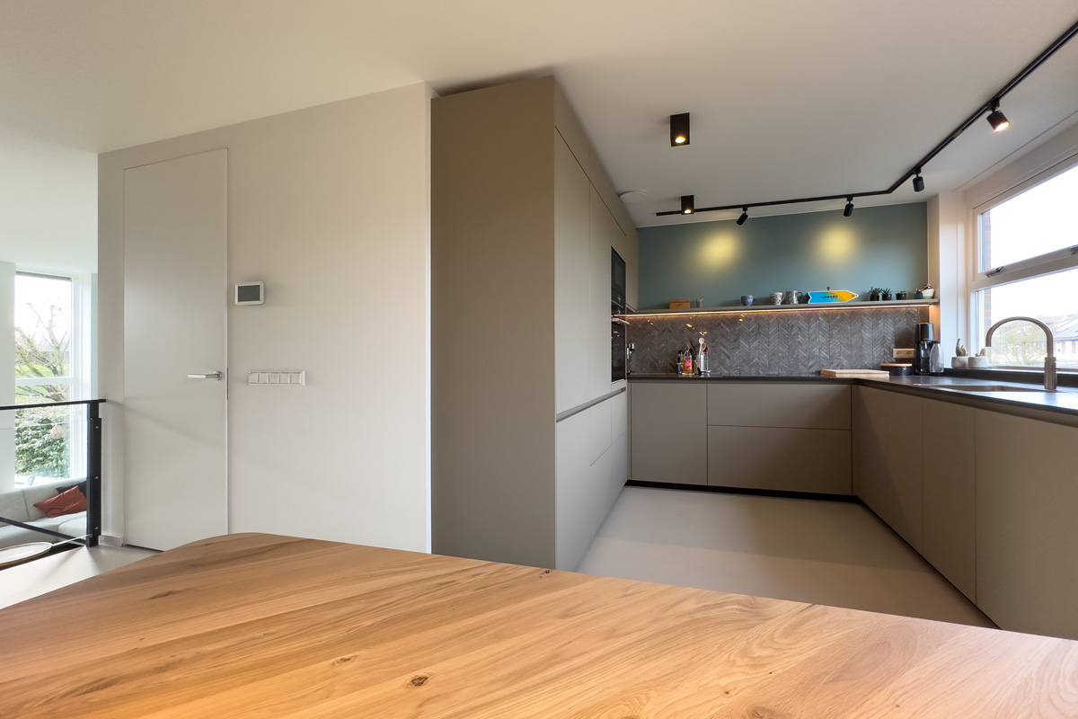 Moderne keuken op maat met visgraat wandtegels, luxe ingebouwde apparatuur en een houten tafel in een stijlvol interieur in Amersfoort.