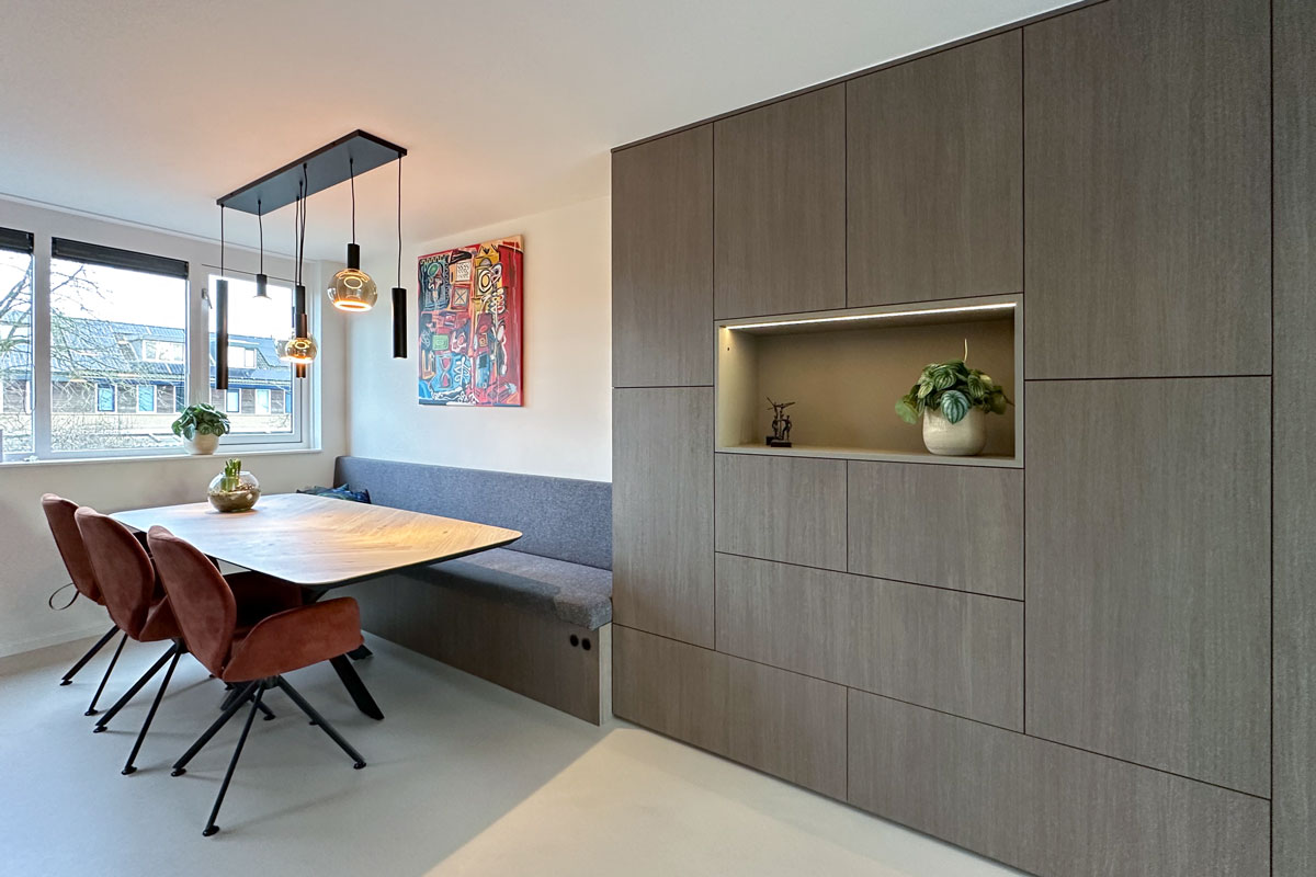 Moderne eetkamer met een kast op maat, geïntegreerde bank en sfeervolle verlichting in een woning in Amersfoort.