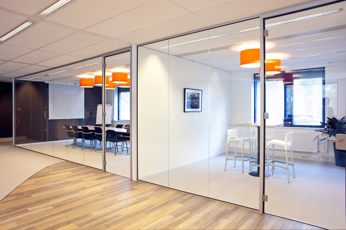 Moderne vergaderruimte in Zeist met glazen wanden, houten vloer en oranje hanglampen.
