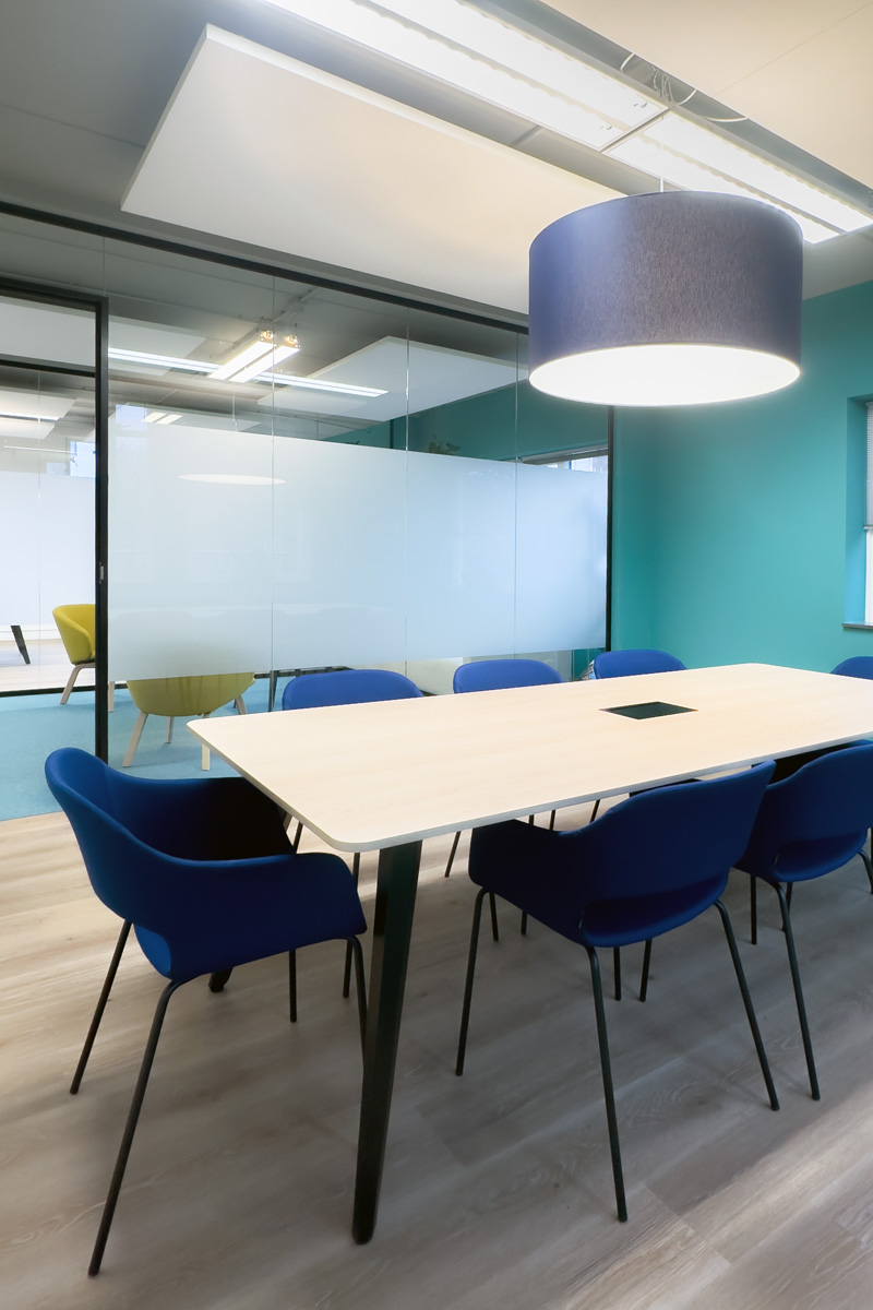 Kantoorinrichting Amsterdam: moderne vergaderruimte met blauwe stoelen, houten tafel en glazen wanden bij Staij.