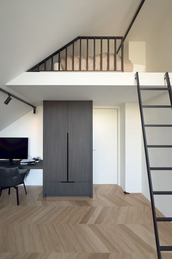 Moderne slaapkamer met een op maat gemaakte kledingkast, een bureau in dezelfde stijl en een speelse vide met een zwart metalen balustrade en ladder.