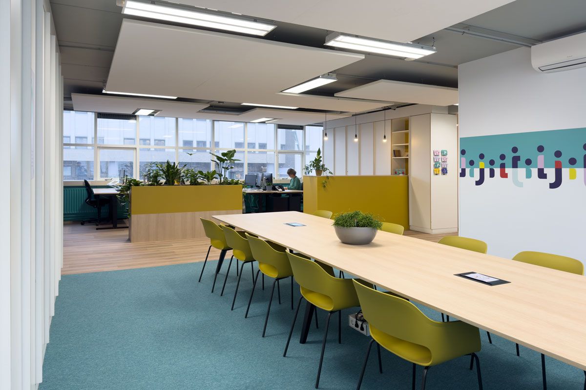 Moderne kantoorinrichting in Amsterdam met grafische prints in de huisstijl van Staij en een grote lunch- en vergadertafel.