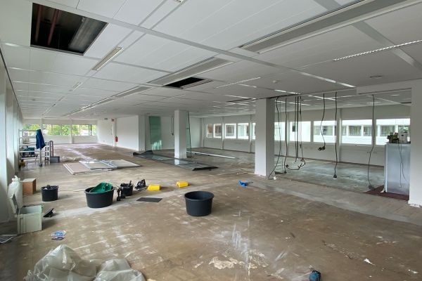 Lege kantoorruimte in renovatie met open plafond, gereedschap op de vloer en glazen panelen. Voorbereiding voor nieuwe kantoorinrichting.