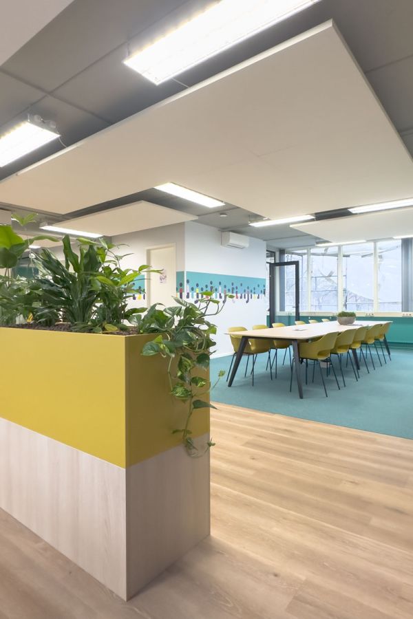 Kantoorinrichting voor Staij met plantenbak en vergadertafel. In het kantoor interieur zijn de kleuren van de huisstijl toegepast.