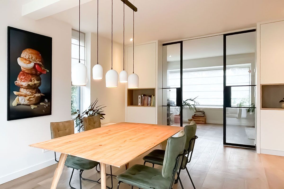 Moderne eetkamer met houten tafel, hanglampen en kasten op maat.