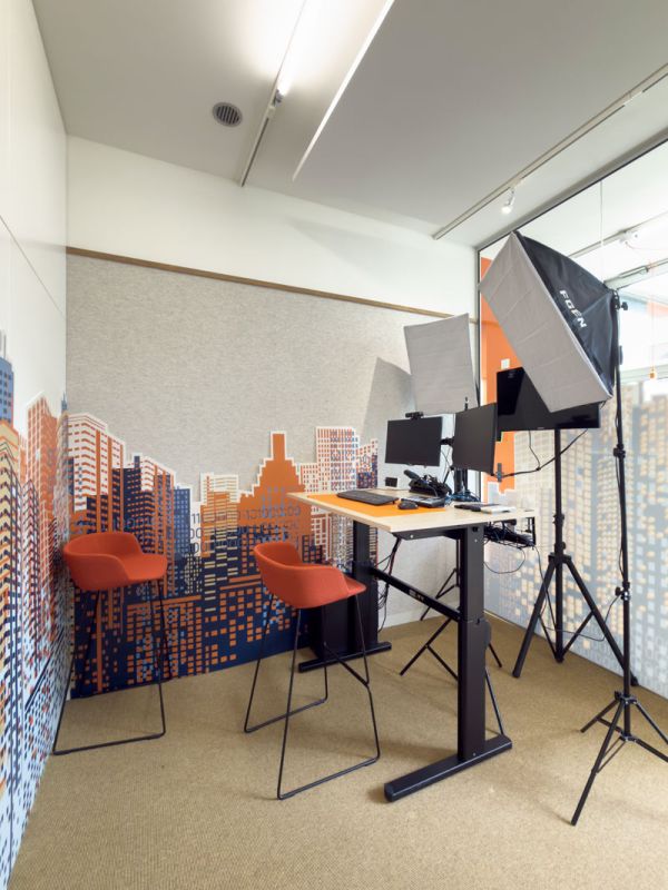 Videostudio met oranje stoelen, zit-sta bureau en studioverlichting