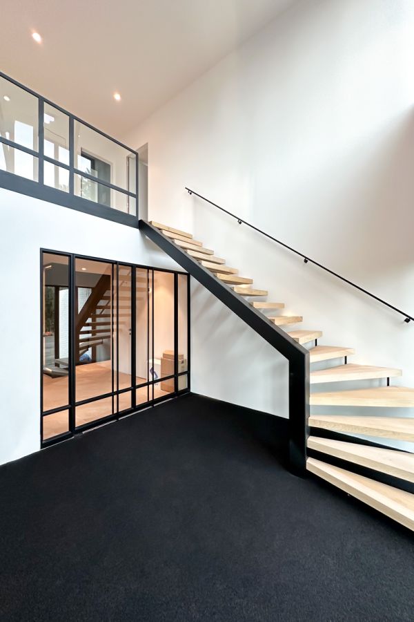 Entree luxe woning met eikenhouten trap, stalen deuren en design railing.