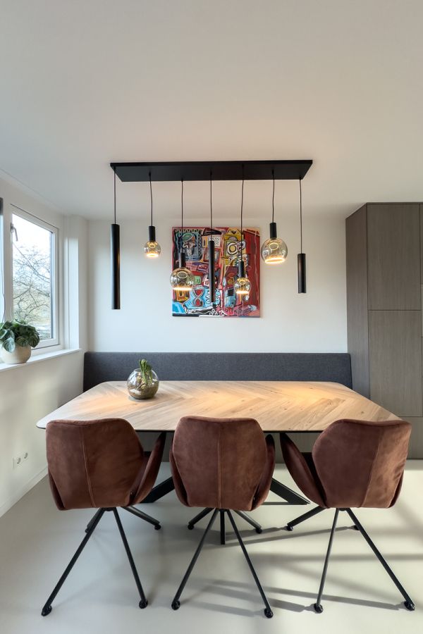 Stijlvolle eethoek met houten tafel, moderne verlichting en maatkast in een op maat ingericht interieur in Amersfoort.
