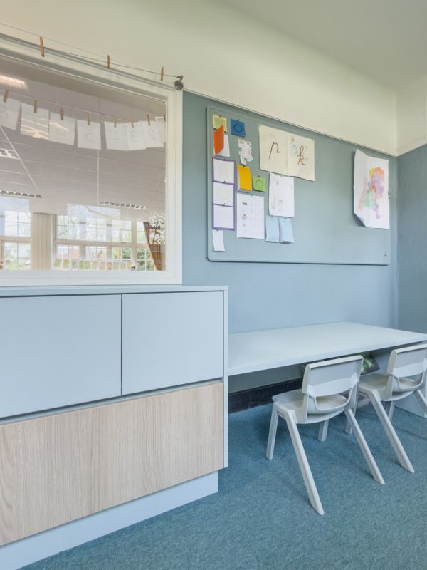 Kast op maat met werkplek en 2 stoelen in zachtblauwe kleur met lichte houtprint.