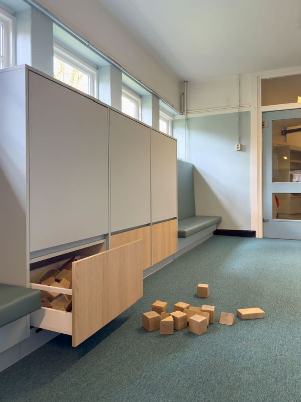 Opbergkast voor kleuters met banken om te lezen.