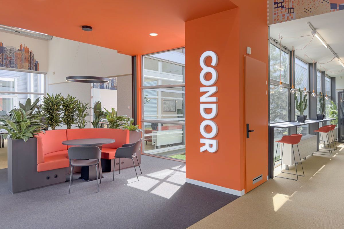 Kantoorontwerp voor Condor in Amersfoort met oranje zithoek en bartafel bij de ramen.