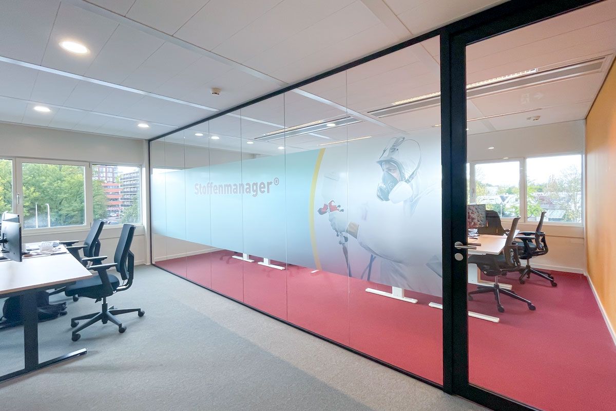 Glazen systeemwand bedrukt met het logo, in combinatie met een rode vloerbedekking.