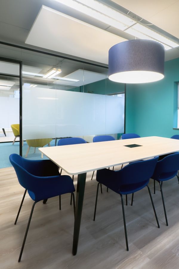 Kantoorinrichting Amsterdam: moderne vergaderruimte met blauwe stoelen, houten tafel en glazen wanden bij Staij.