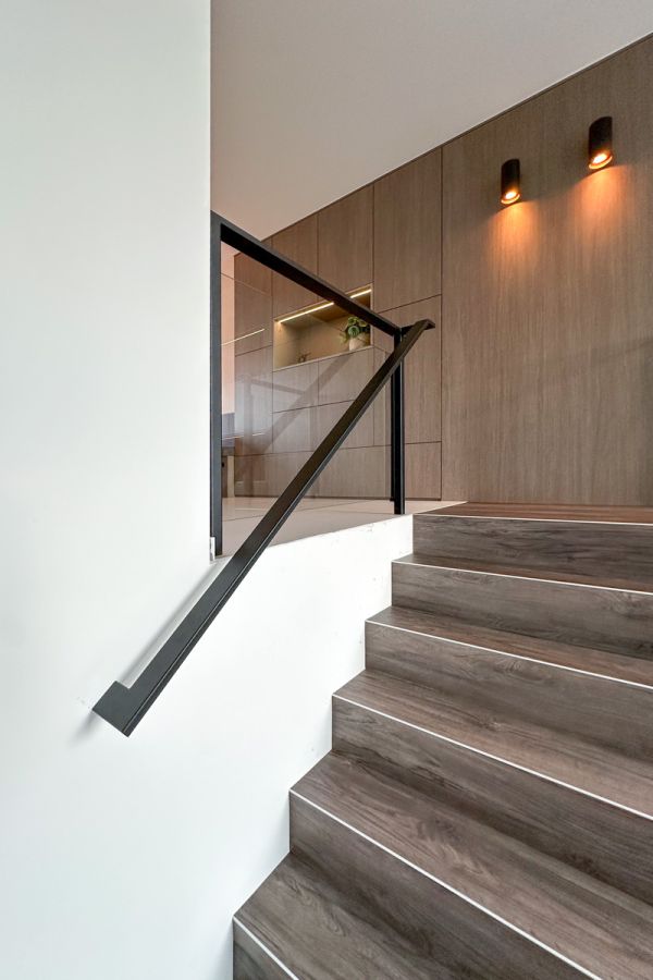 Stijlvolle trap met stalen balustrade op maat en geïntegreerde verlichting, ontworpen voor een modern interieur in Amersfoort.