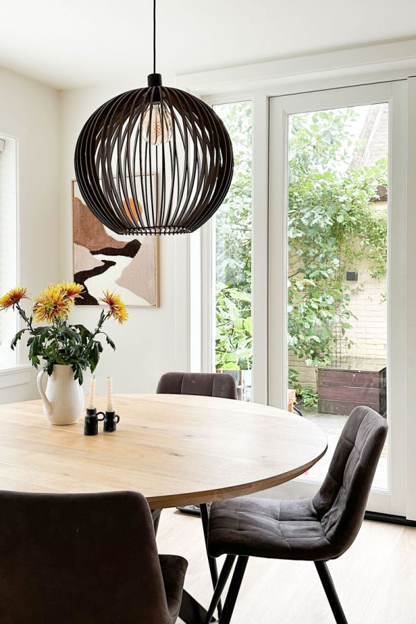 Eetkamer met glas-in-lood en suite deuren, ronde tafel en zicht op tuin in jaren 30 woning.