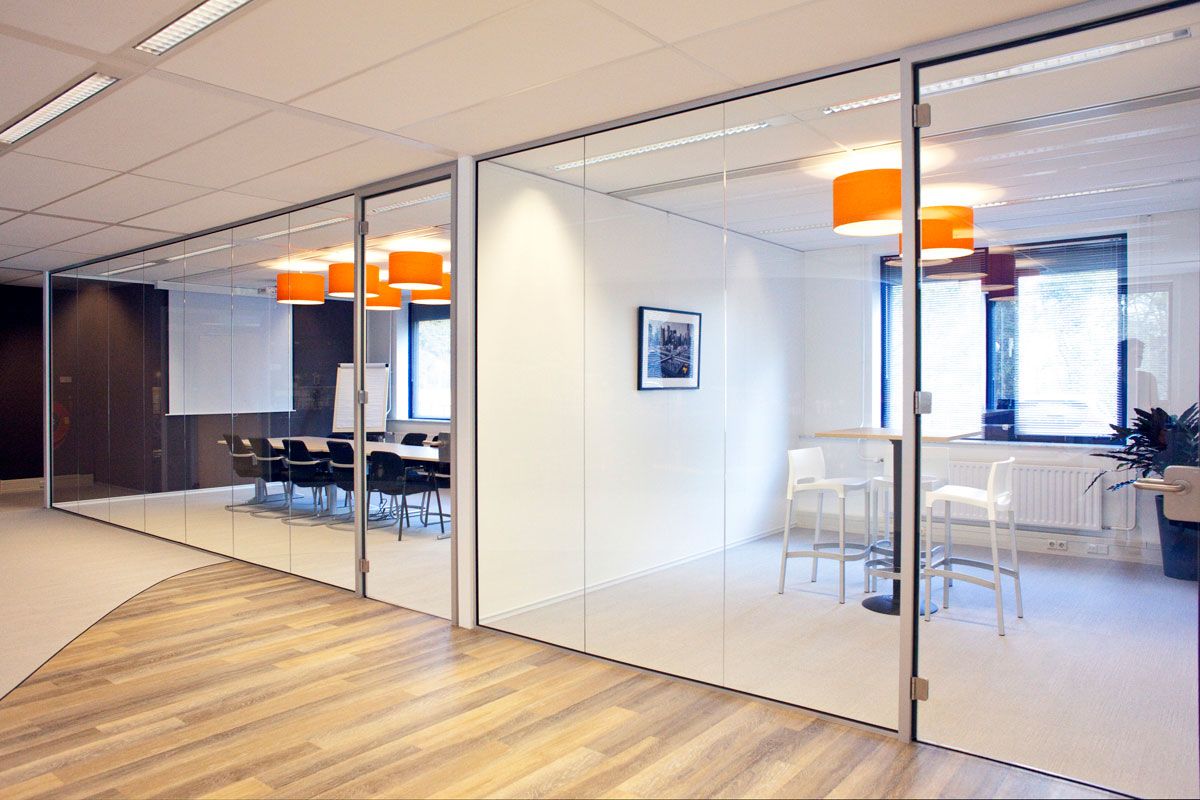 Moderne vergaderruimte in Zeist met glazen wanden, houten vloer en oranje hanglampen.