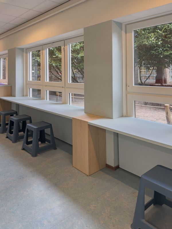 Werkplek in de gang met zicht op het schoolplein van basisschool Pallas Athene.