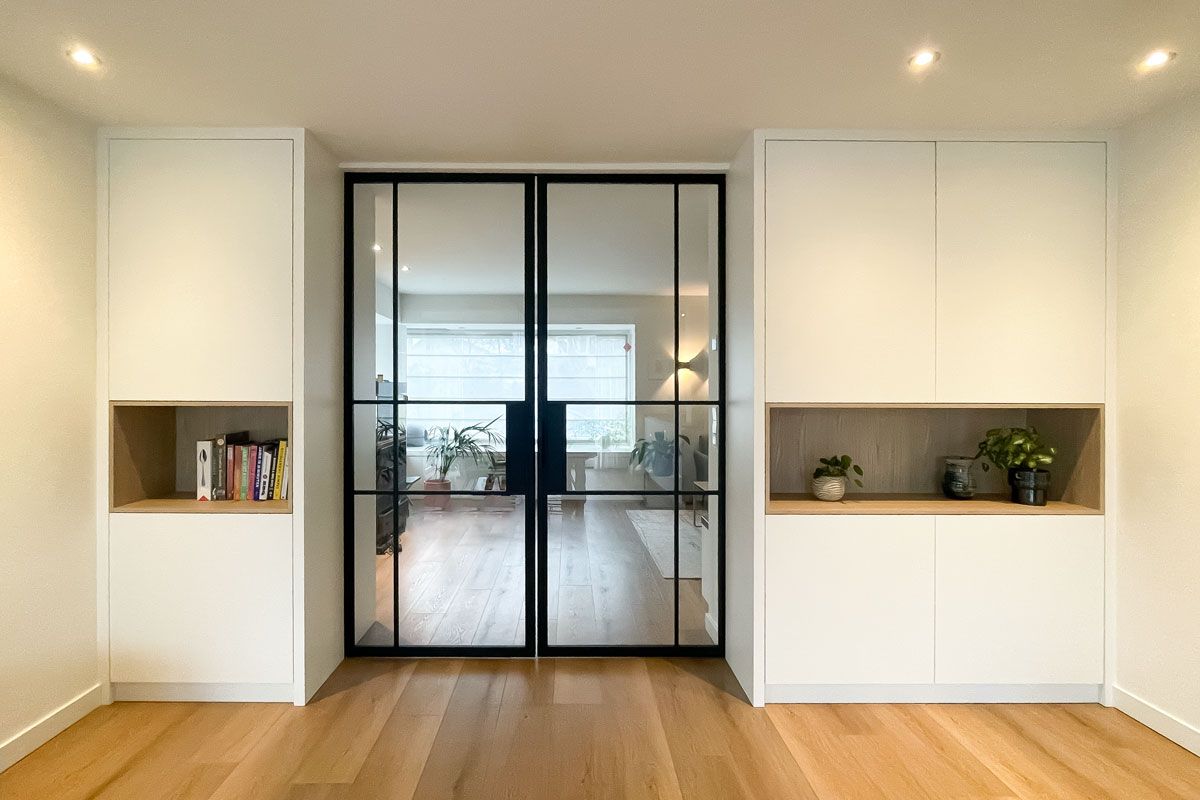 Woonkamer interieurontwerp met stalen schuifdeur en kasten op maat.