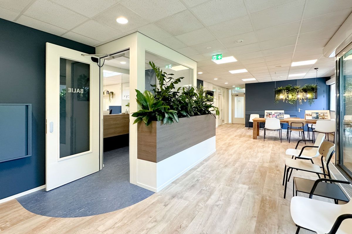 Wachtkamer van Huisartsenpraktijk Vogelplein met moderne inrichting, frisse kleuren en veel planten.