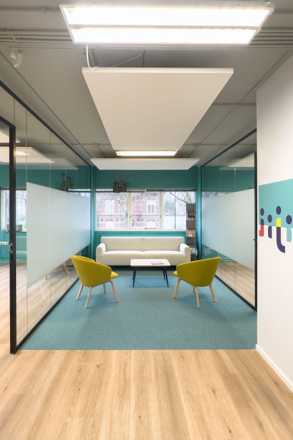 Ontvangstruimte in het kantoorontwerp van Staij in Amsterdam met groene accenten, glazen wanden en moderne zitplaatsen.