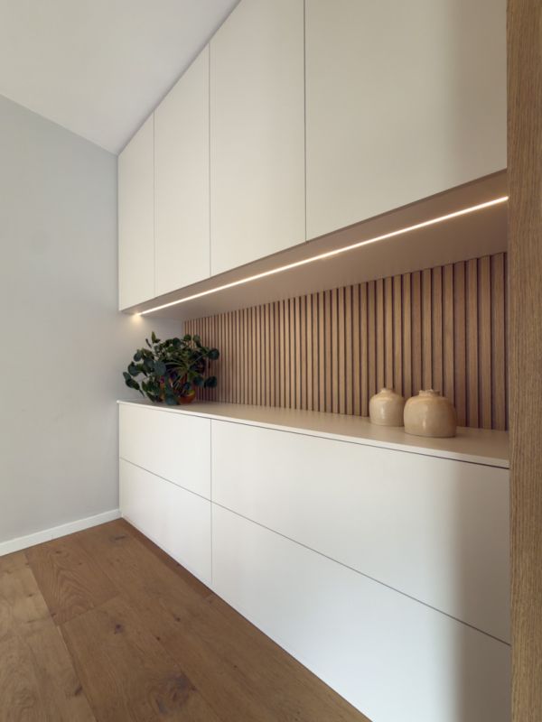 Kast op maat met brede lades in een beige kleur en hoge bovenkasten. De achterwand heeft houten latjes.