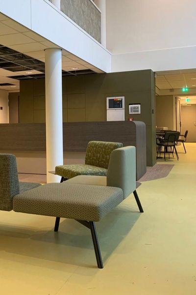 Ontvangstruimte GGZ-instelling met moderne, groene inrichting en comfortabele zitplaatsen.