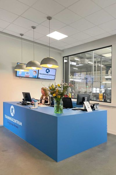 Receptiebalie van het trainingscentrum Zorggroep Almere met blauwe toon en moderne verlichting.