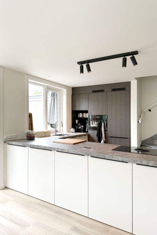 Moderne keuken in jaren 30 woning met lichtgrijs werkblad en ingebouwde kast.