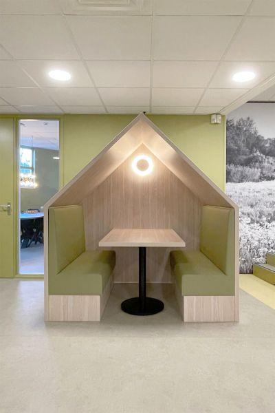 Treinbankjes in huisjesvorm met houten afwerking en groene bekleding op het leerplein van basisschool De Vos.