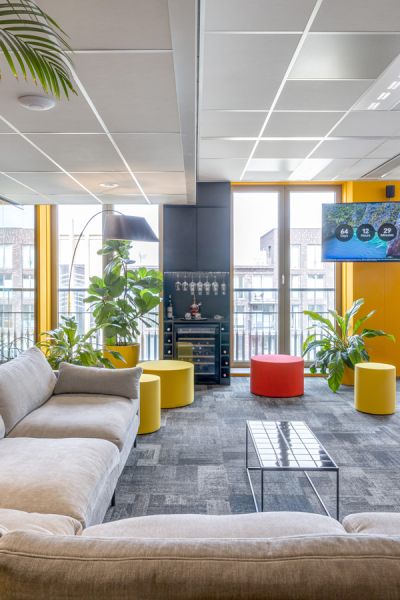 Kantoorinrichting Amsterdam: sfeervolle lounge bij VIP Response met gele en rode accenten, veel groen en moderne inrichting.