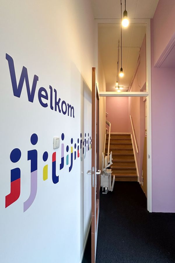 Kantoortuin met vergadertafel, planten, gele stoelen en een blauwe muur.