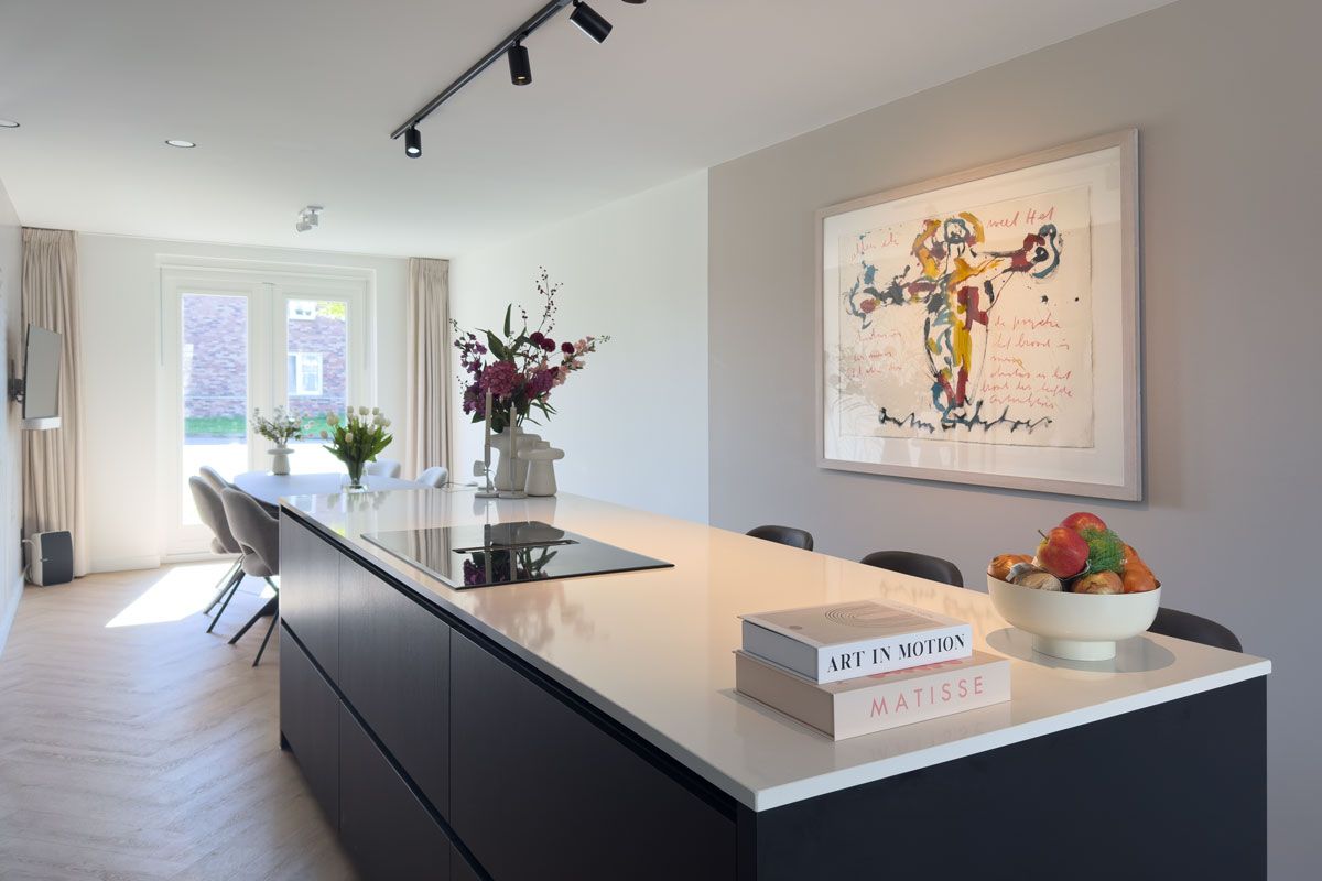 Zwart keukeneiland met barkrukken en kookeiland met krukken en verlichting.