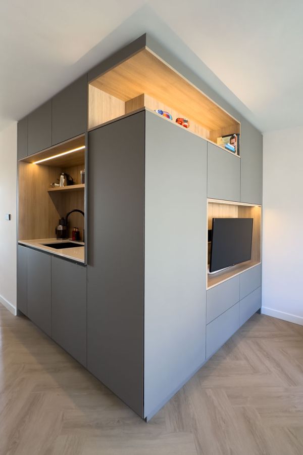 Wandkast op maat met geïntegreerde keuken en tv-meubel in moderne woning.