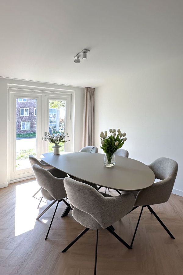 Moderne inrichting met ovale tafel en gestoffeerde stoelen.