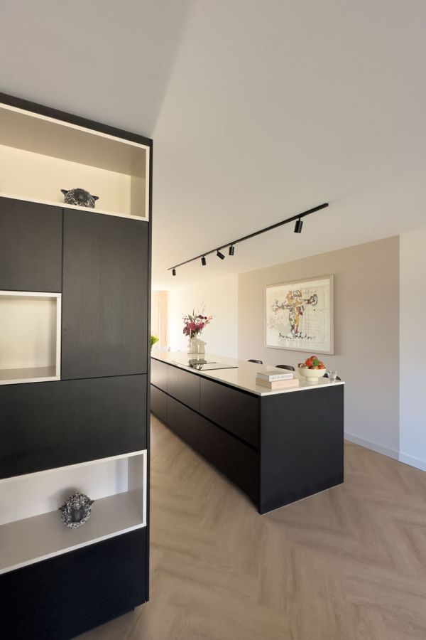 Zwarte maatwerk kast en keuken op maat in een open interieur.