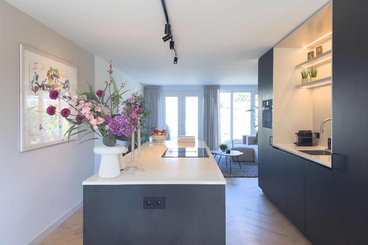 Zwart keukeneiland met barkrukken en kookeiland met krukken en verlichting.